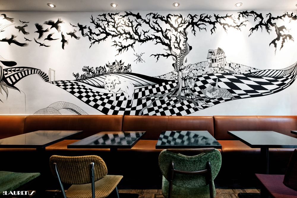 Wall mural by Cil Laurens in a bar interior, checkerboard floor and white fox